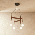 Clérachic's chandelier in dark red mahogany wood, four frosted glass globes hanging from its branching frame.