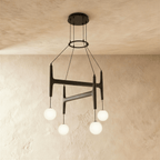 Clérachic's chandelier in black walnut wood, four frosted glass globes hanging from its branching frame.