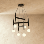 Clérachic's chandelier in black walnut wood, six frosted glass globes suspended from its layered frame.
