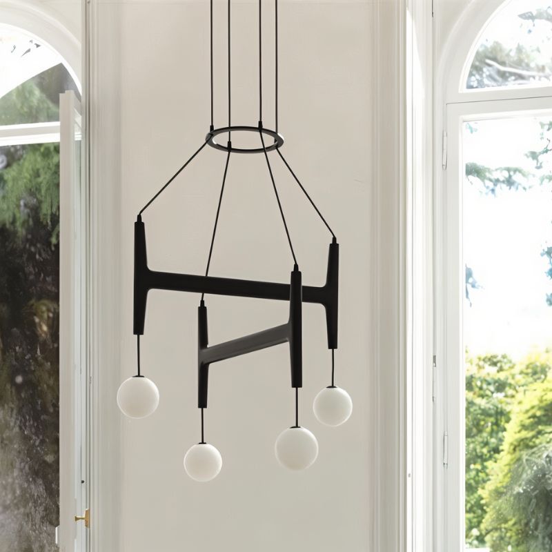 Clérachic's chandelier in black walnut wood, its four frosted globes glowing beside a garden-view window.