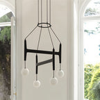 Clérachic's chandelier in black walnut wood, its four frosted globes glowing beside a garden-view window.