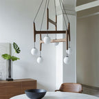 Clérachic's chandelier in mahogany wood, its six frosted globes suspended above a round dining table.