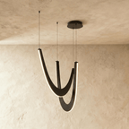 Clérachic chandelier of three boomerang-shaped oak loops in black wood, edge-lit in warm white on fine suspension wires.
