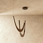 Clérachic chandelier of three boomerang-shaped oak loops in dark wood, edge-lit and hanging from a black round canopy.