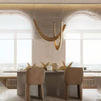 Clérachic light wood chandelier of curved oak loops above a speckled stone dining table with soft tan chairs.