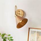 Looking up into the lit walnut-colour cone shade of this Clérachic wall light, with green leaves and a framed print nearby.