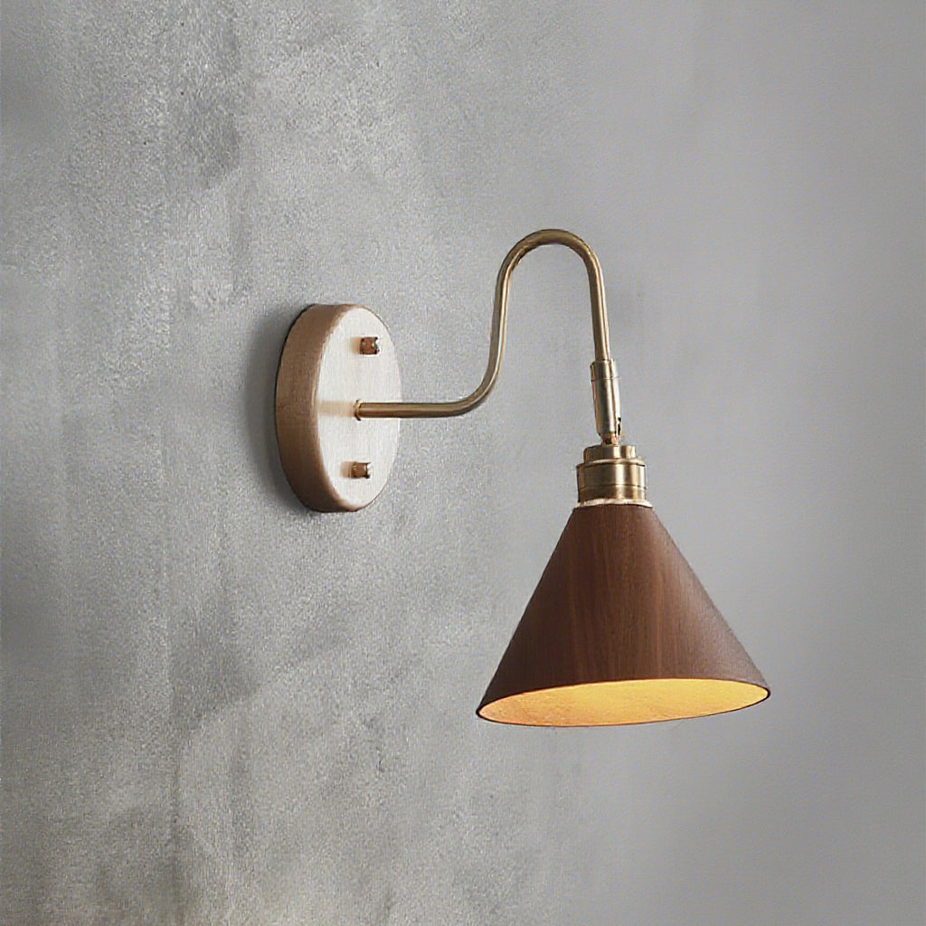 Lit walnut-colour cone shade on a brass gooseneck arm, this Clérachic wall light mounted on a textured grey wall.