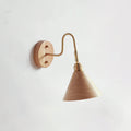 Side-on view of a wood-colour cone shade and brass gooseneck arm on a Clérachic wall light against a pale wall.