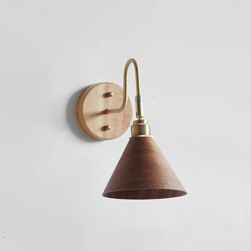 Walnut-colour cone shade under a brass gooseneck arm with a pale wooden backplate, this Clérachic wall light on a white wall.