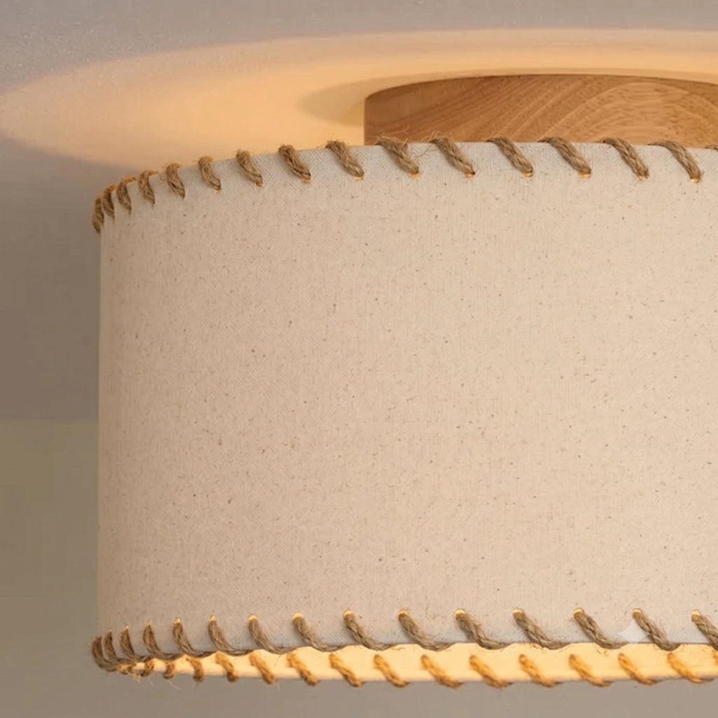 Close view of the rope stitching along the hem and the oak-toned canopy on this Clérachic ceiling light, with warm light glowing beneath the shade.
