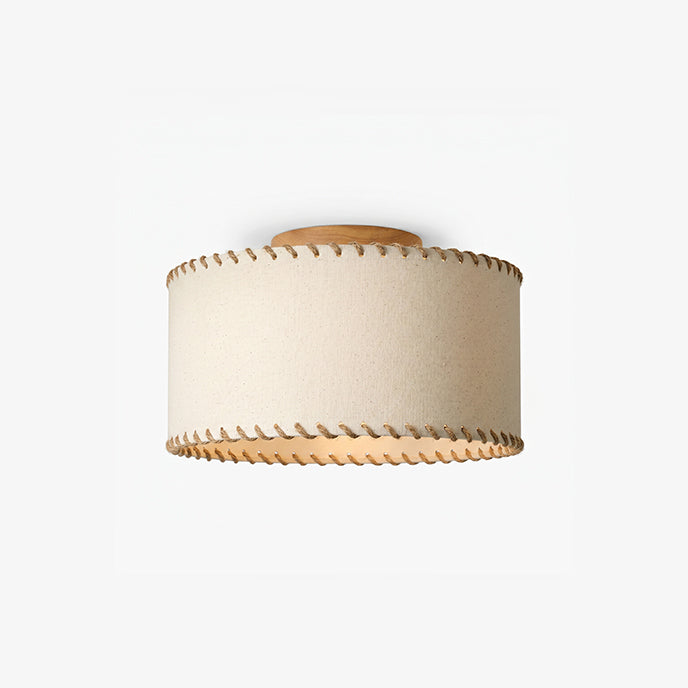 Smaller, distant view of a Clérachic flush-mount drum light in beige linen with a wood canopy, shown unlit on a light backdrop.