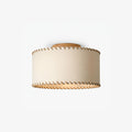 Smaller, distant view of a Clérachic flush-mount drum light in beige linen with a wood canopy, shown unlit on a light backdrop.