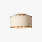 Smaller, distant view of a Clérachic flush-mount drum light in beige linen with a wood canopy, shown unlit on a light backdrop.
