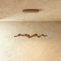 Clérachic wavy ribbon chandelier in warm wood tones, hung on two fine cables from an oval wooden canopy against a limewashed wall.