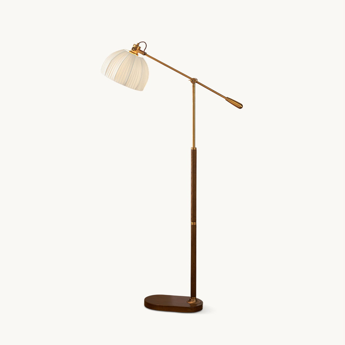 Walnut colour Clérachic floor lamp on a plain white backdrop, with a pleated beige dome shade on a long brass arm and an oval wooden base.