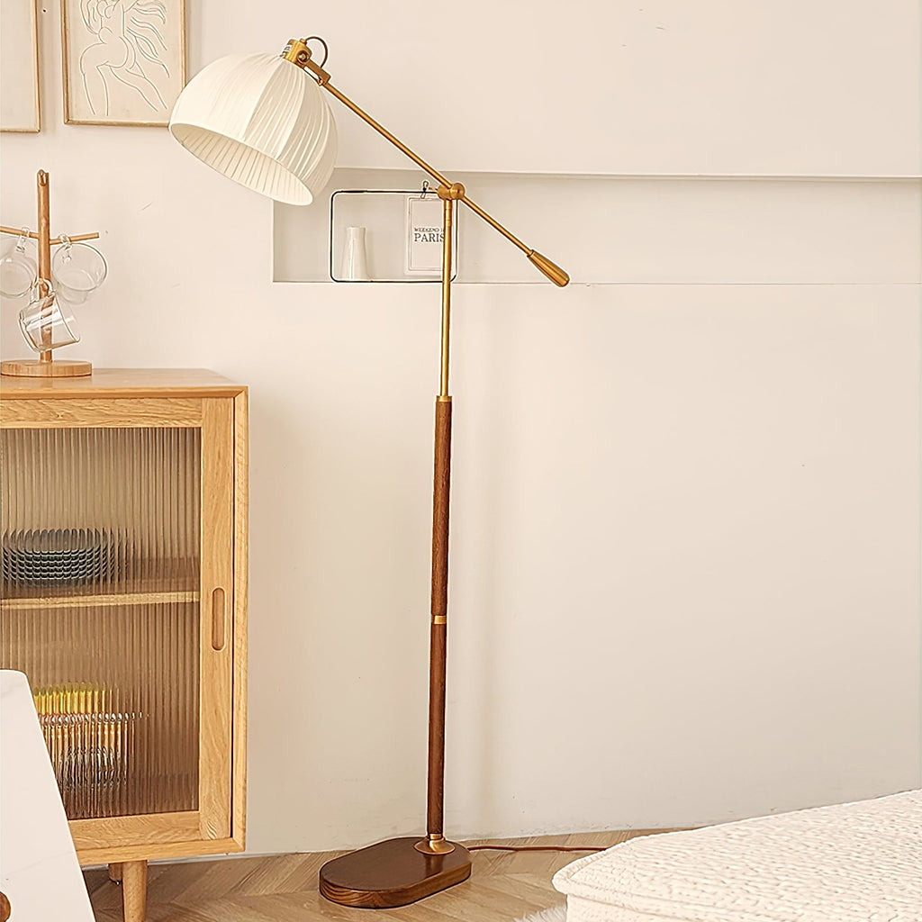 Clérachic floor lamp beside a light wood cabinet with ribbed glass doors, its arm swung out and the pleated shade tilted down.