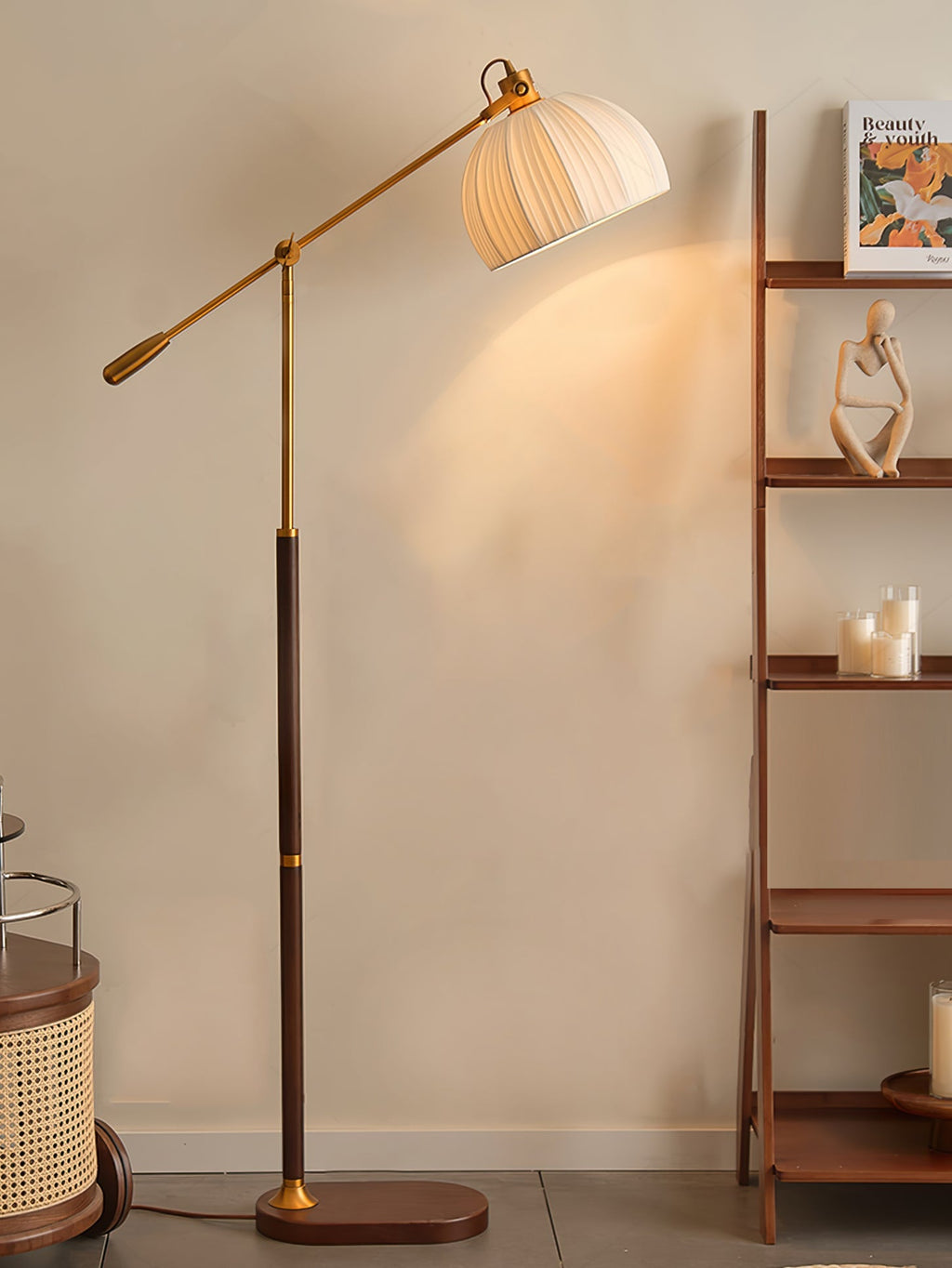Clérachic floor lamp with its long arm reaching out beside a walnut ladder shelf holding candles and a small figurine.