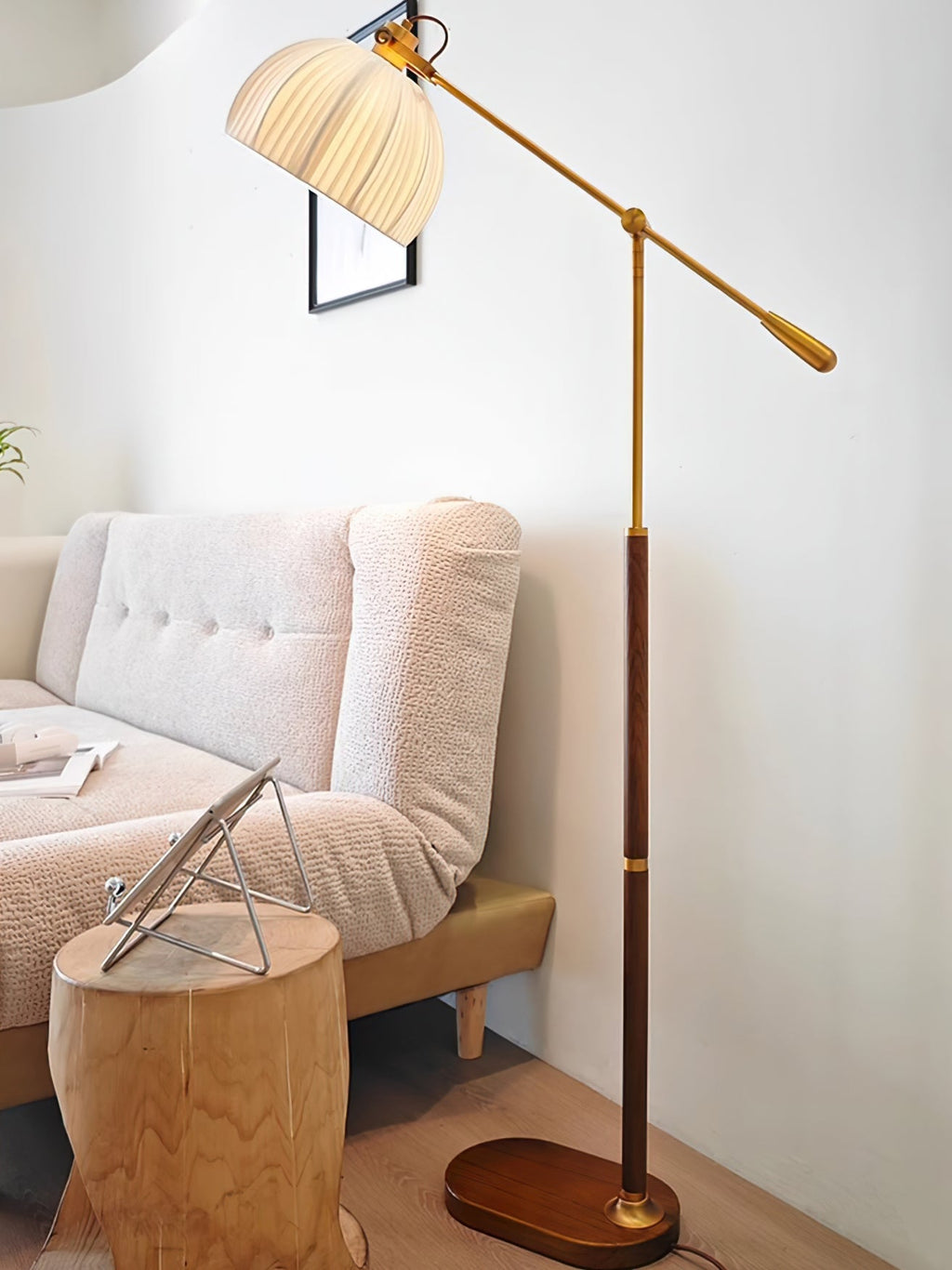 Clérachic floor lamp in a corner with a pale sofa and a rounded wooden stool holding a tablet, the arm stretched over the room.