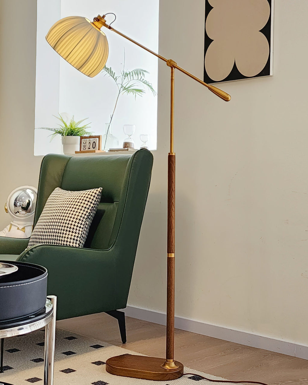 Lit Clérachic floor lamp with its pleated shade high above a green armchair, a round side table and a patterned rug.