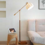 Clérachic floor lamp beside a textured grey sofa and a hollow wooden stool with a tablet, the arm angled back from the wall.
