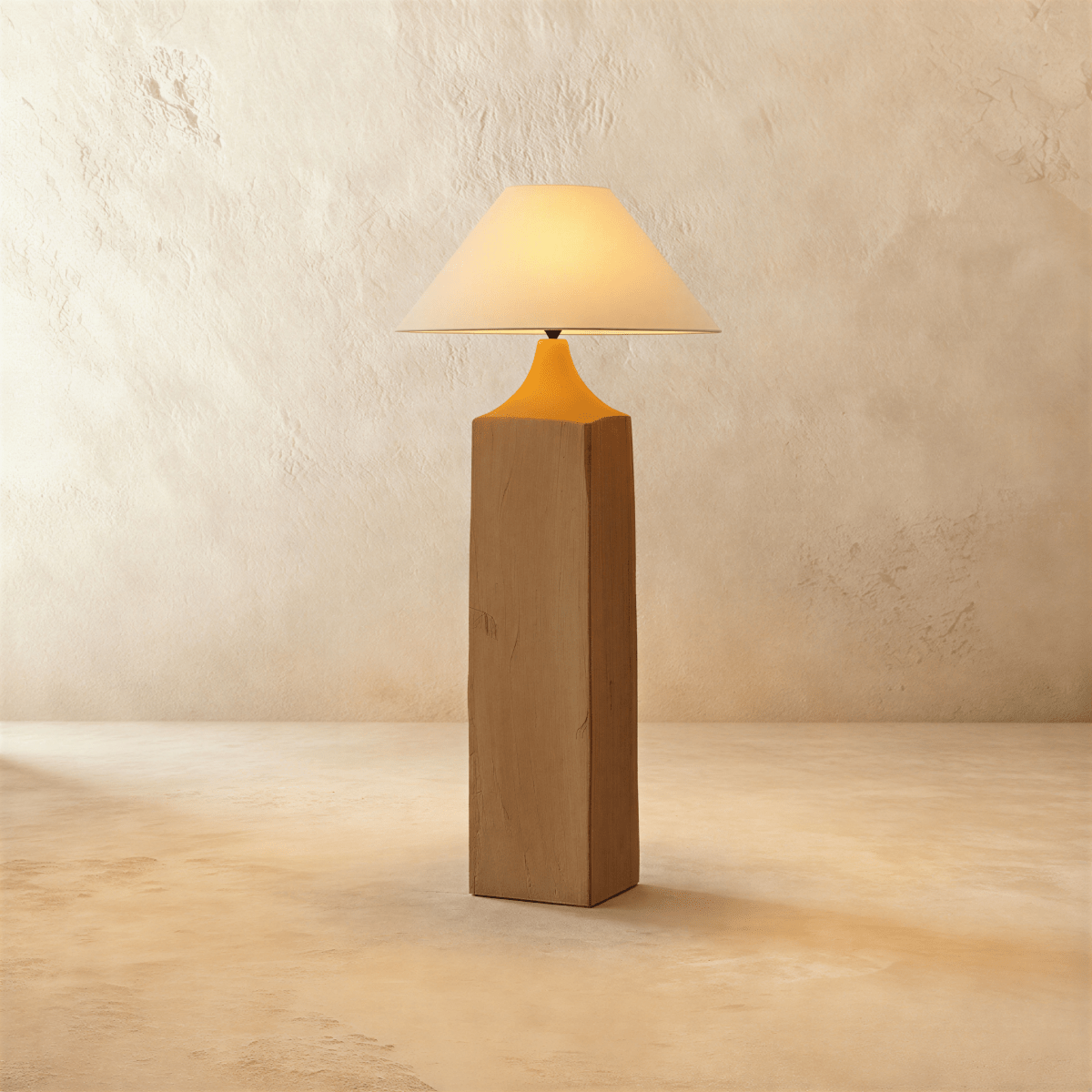 Clérachic floor lamp with a square raw-wood post, a tapered amber-orange neck and a wide linen cone shade glowing warm on limewash.