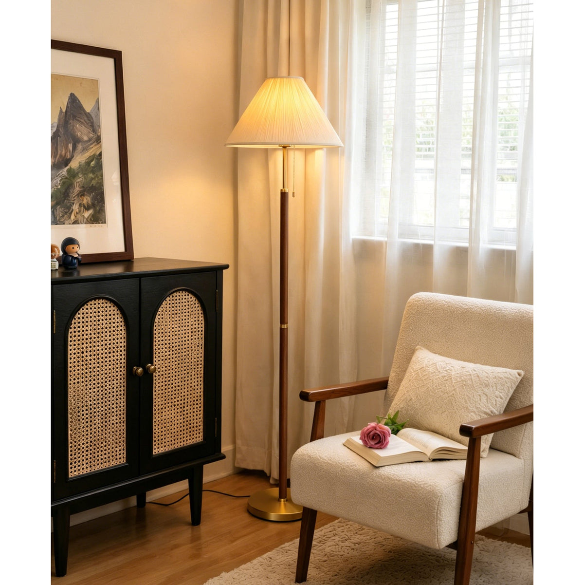 Lit warmly beside a sheer-curtained window, this Clérachic floor lamp stands near a cane-doored black cabinet and an armchair with an open book.
