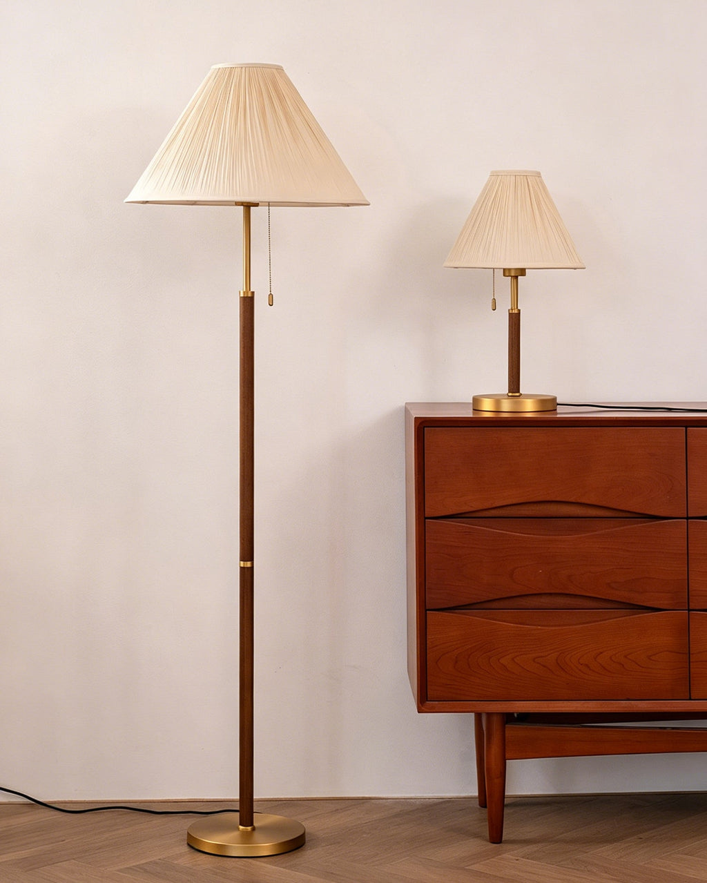 Unlit, this Clérachic floor lamp stands taller than the pleated table lamp on the walnut drawer chest beside it, against a soft pink-white wall.