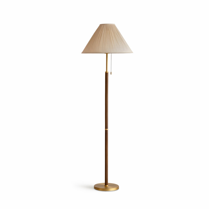 Clérachic floor lamp on a white backdrop, with the pleated beige shade, thin walnut-toned stem, brass collar, pull chains and brass base.