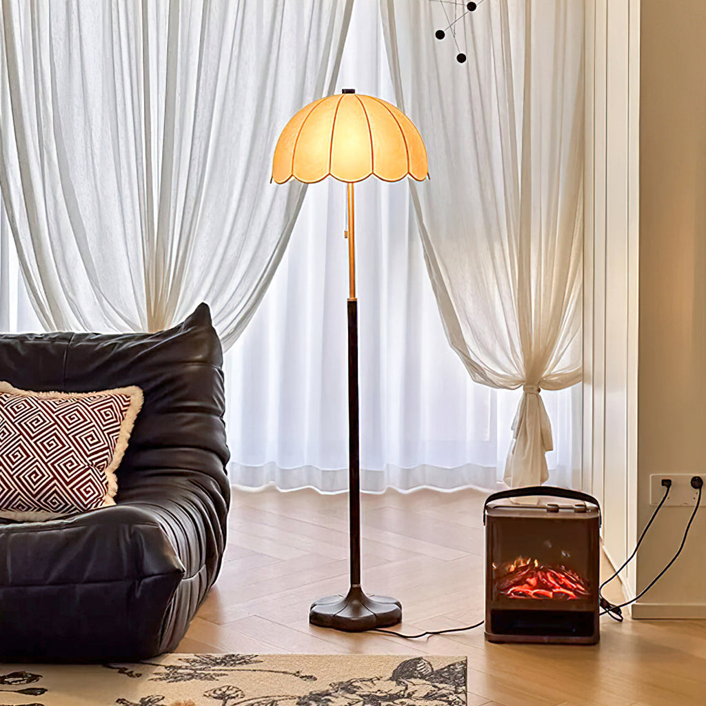 A Clérachic floor lamp lit between sheer white curtains, with a black leather lounger and a small electric fire on a herringbone floor.