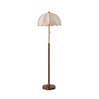 Cut-out view of this Clérachic floor lamp with a walnut-toned stem, brass neck and white scalloped shade, on a white backdrop.