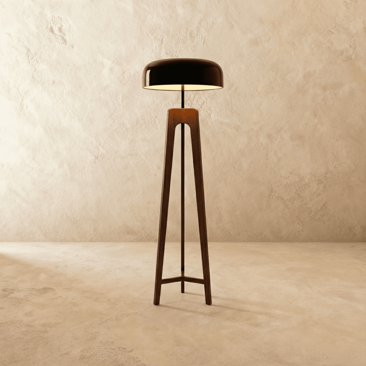 Clérachic tall tripod floor lamp in dark stained wood with a black disc shade, lit, on a limewash backdrop.