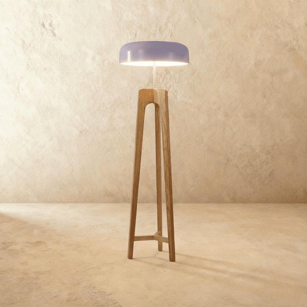 Clérachic tall light oak tripod floor lamp with a lilac disc shade glowing warmly against a limewash wall.