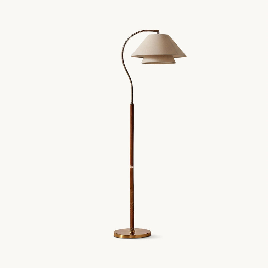 This Clérachic floor lamp on a plain white backdrop, with a two-tier linen shade on a curved brass arm and a walnut stem.