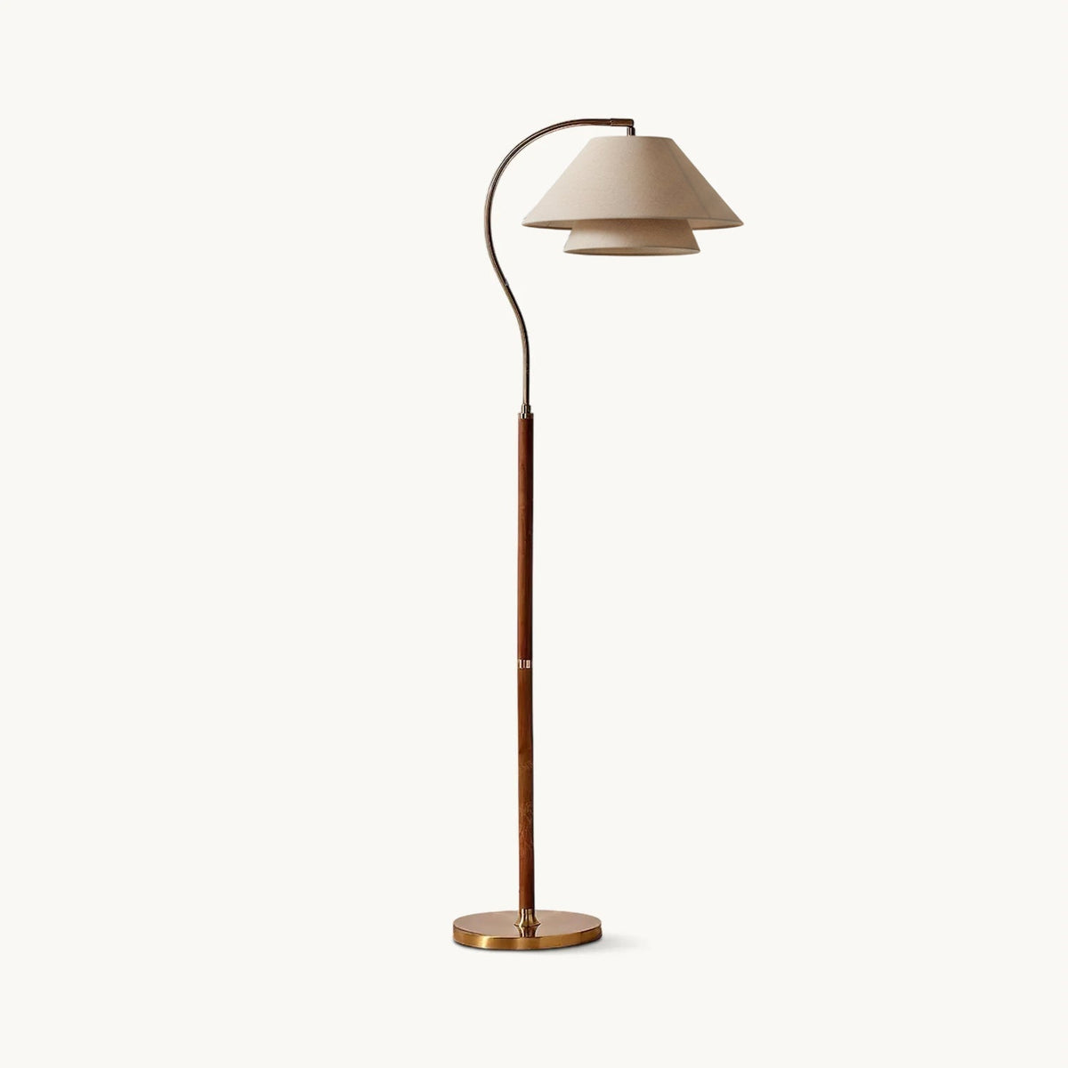 This Clérachic floor lamp on a plain white backdrop, with a two-tier linen shade on a curved brass arm and a walnut stem.