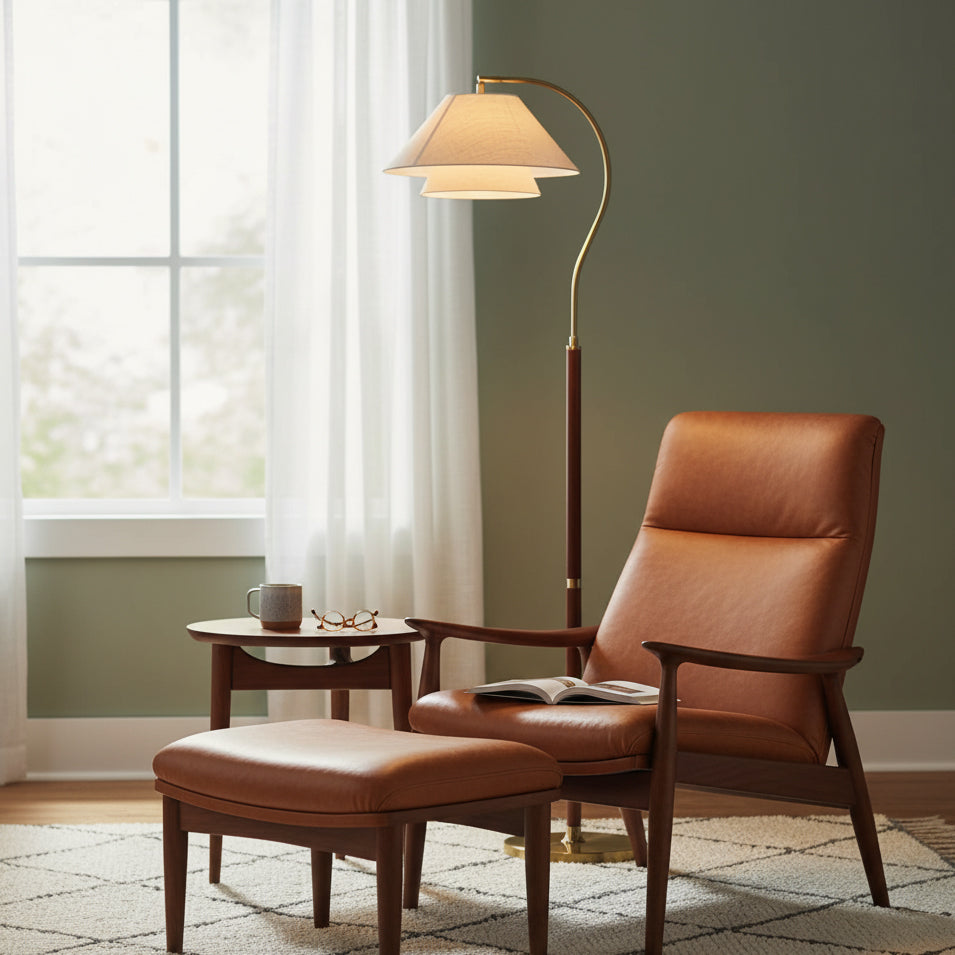 Clérachic floor lamp arching over a tan leather recliner and footstool, against a sage-green wall with white curtains.