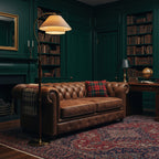 Dark-green library with built-in bookshelves and a tufted leather sofa, lit by this Clérachic floor lamp's glowing shade.