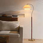 Evening glow from this Clérachic floor lamp, whose layered shade lights a cream wall above a pale armchair.