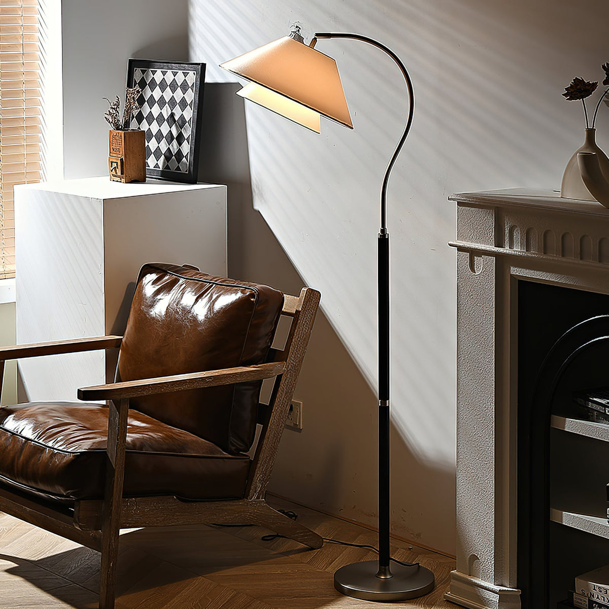 Late sunlight crosses the shade of this Clérachic floor lamp, beside a leather lounge chair and a white fireplace.