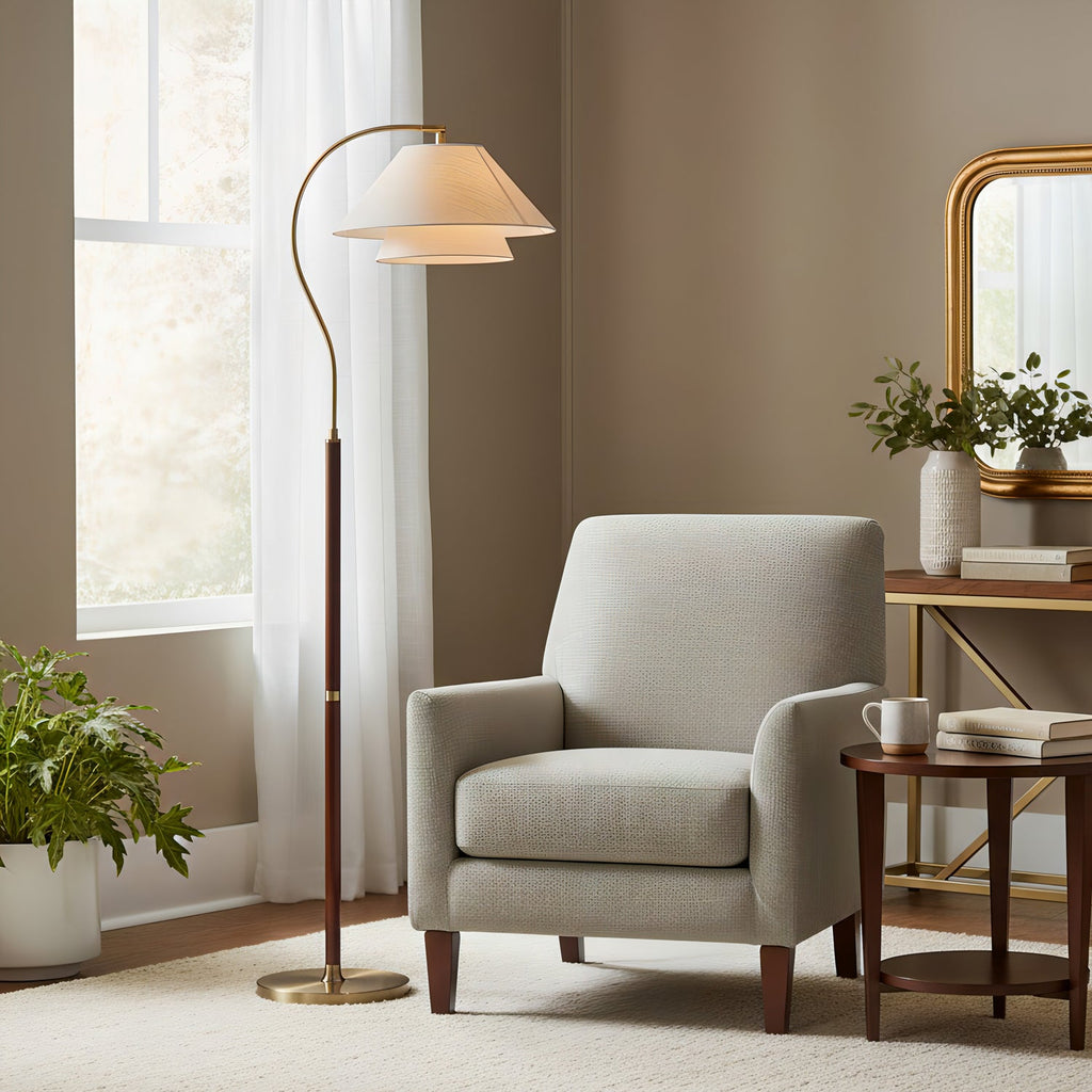 Clérachic floor lamp by a window with sheer curtains, a grey armchair and a gilt mirror, its brass base on a cream rug.