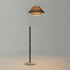 Black-stemmed Clérachic floor lamp with a charcoal shade and a silver base, glowing on a plain grey backdrop.