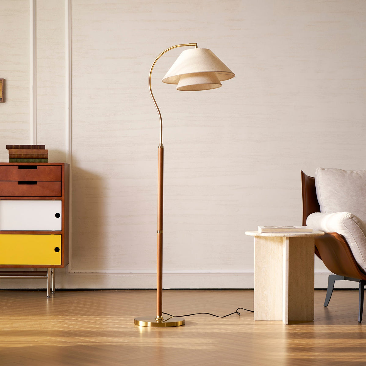 A Clérachic floor lamp on a wooden floor beside a mid-century drawer unit with yellow and white fronts and a stone side table.