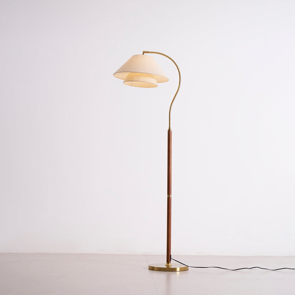 Full-length Clérachic floor lamp, lit, with the two-tier linen shade glowing against a pale studio wall.