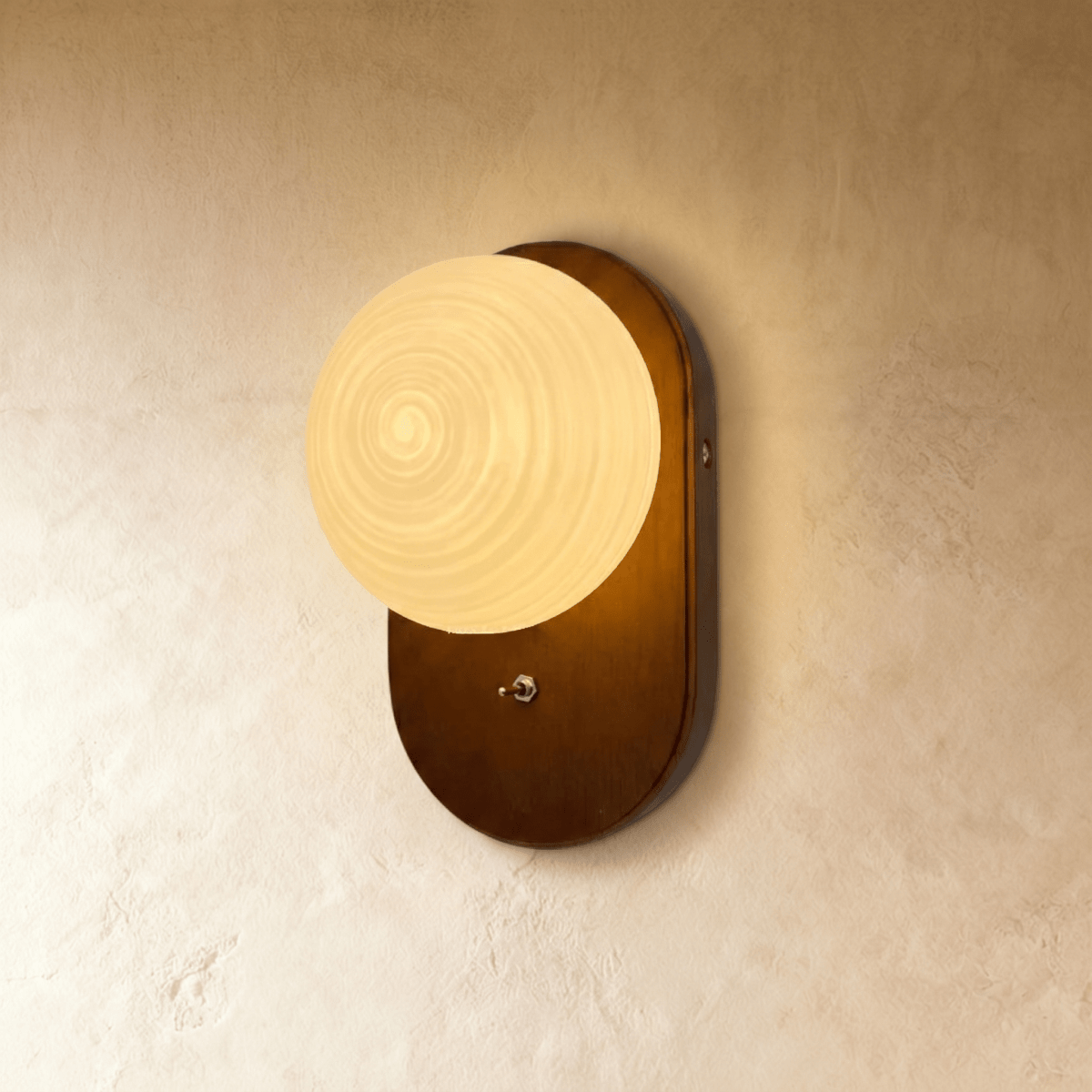 Clérachic wall lamp with a warm wood-toned textured glass globe on an oval walnut backplate, angled view.