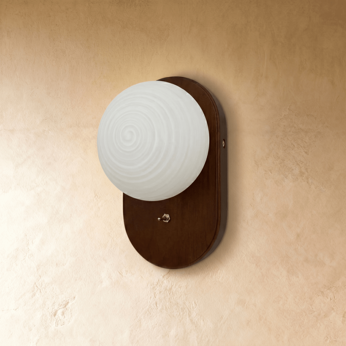 Clérachic wall lamp with a textured glass globe glowing white on an oval walnut backplate, straight-on view.