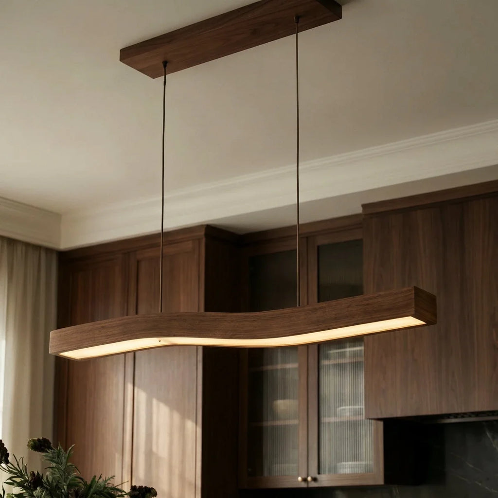 This Clérachic walnut pendant glows warmly against ribbed glass cabinetry and a dark stone kitchen backsplash.