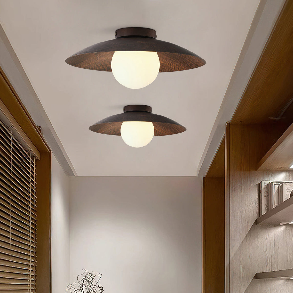 Two Clérachic ceiling lights of different sizes, with walnut-toned shades and frosted globes, in a corridor beside wooden shelving.