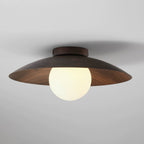 Lit softly, this Clérachic ceiling light has a dark walnut wood-grain shade and a warm glowing frosted globe, on a grey ceiling.