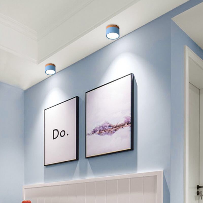 Two blue Clérachic Wood-Grain Cylinder Ceiling Lights washing a pale blue hallway wall above framed prints.