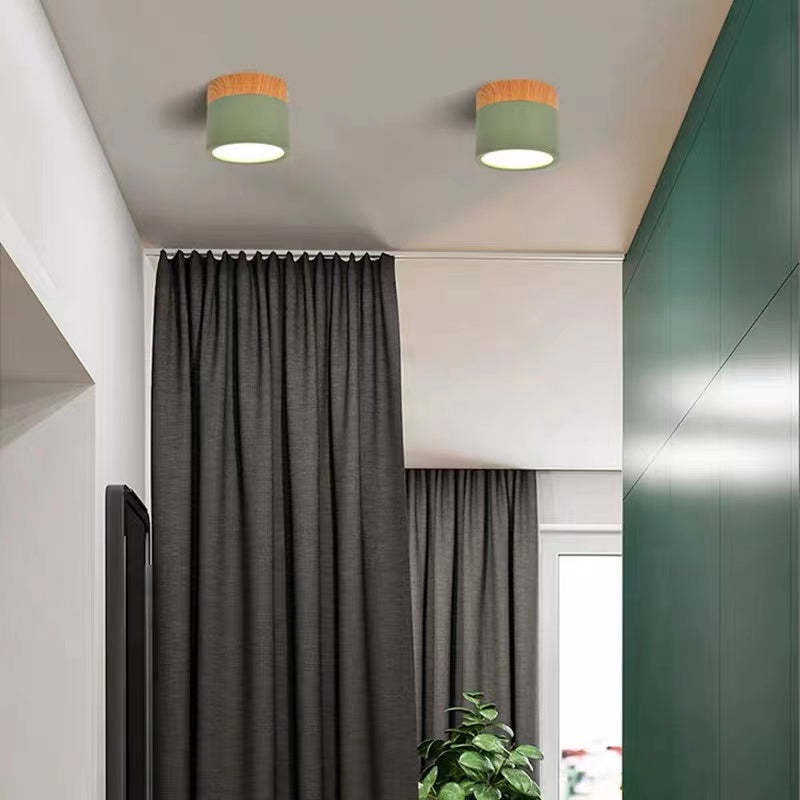 A pair of green Clérachic Wood-Grain Cylinder Ceiling Lights lit on a white ceiling above a curtained hallway.