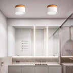 Two white Clérachic Wood-Grain Cylinder Ceiling Lights unlit on a ceiling above a stone vanity and long mirror.